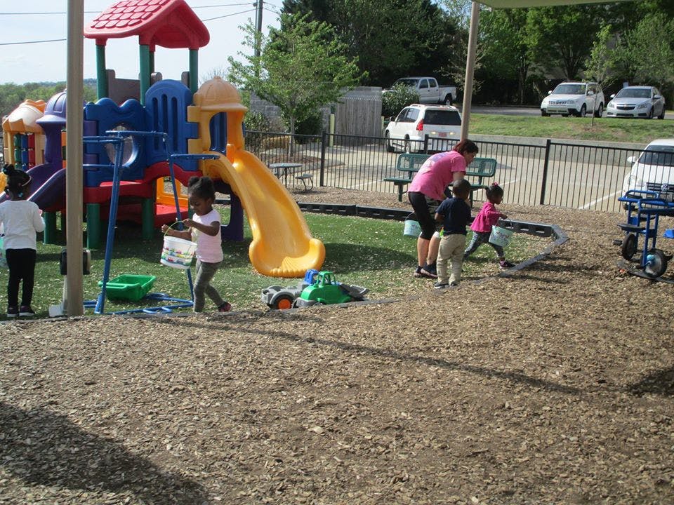 Children and an adult playing on a playground with a slide