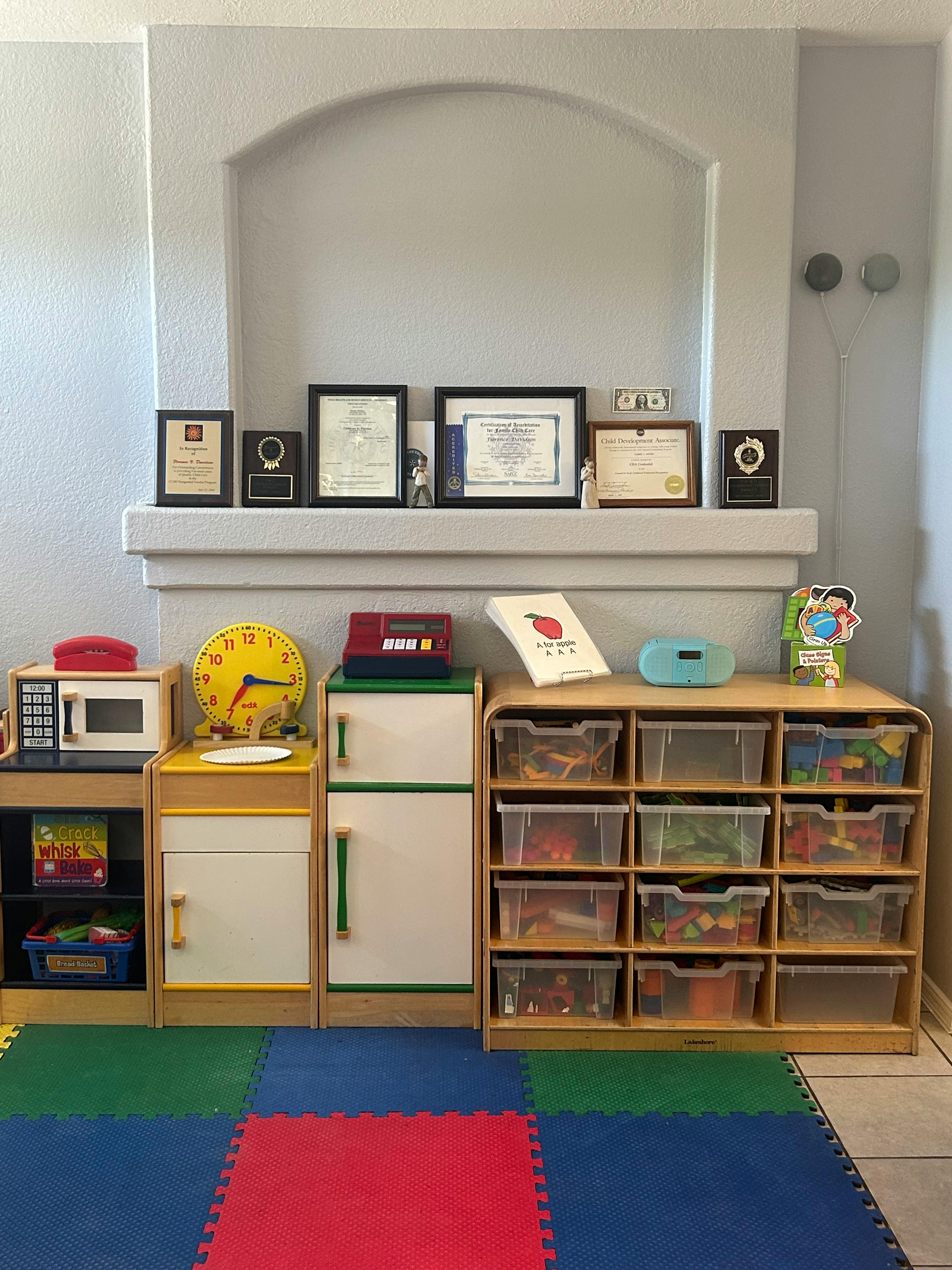 Playroom with toy kitchen, storage shelves, and awards on a mantel