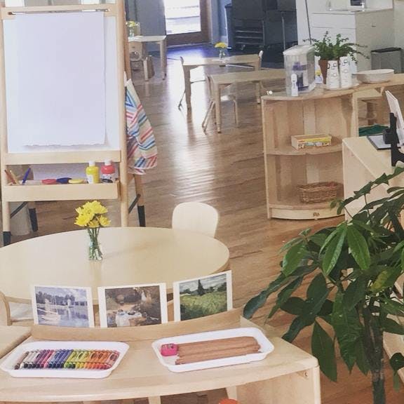 Classroom with an easel, tables, chairs, and art supplies