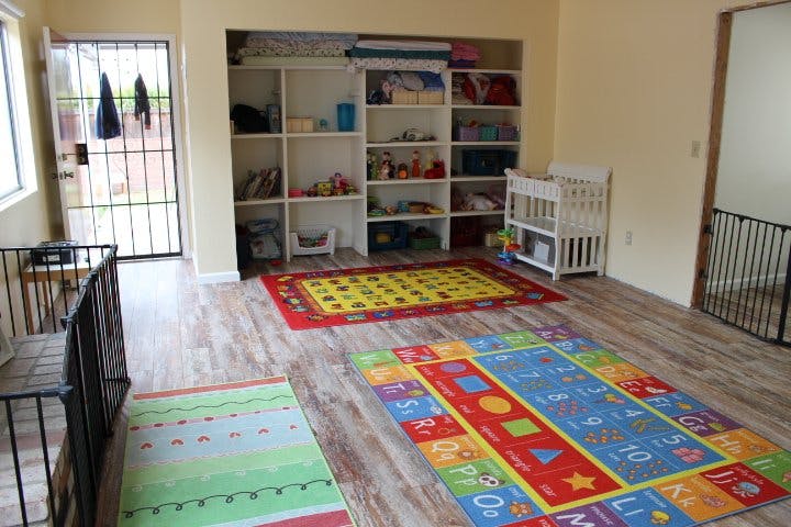Playroom with colorful rugs, shelves, and a crib