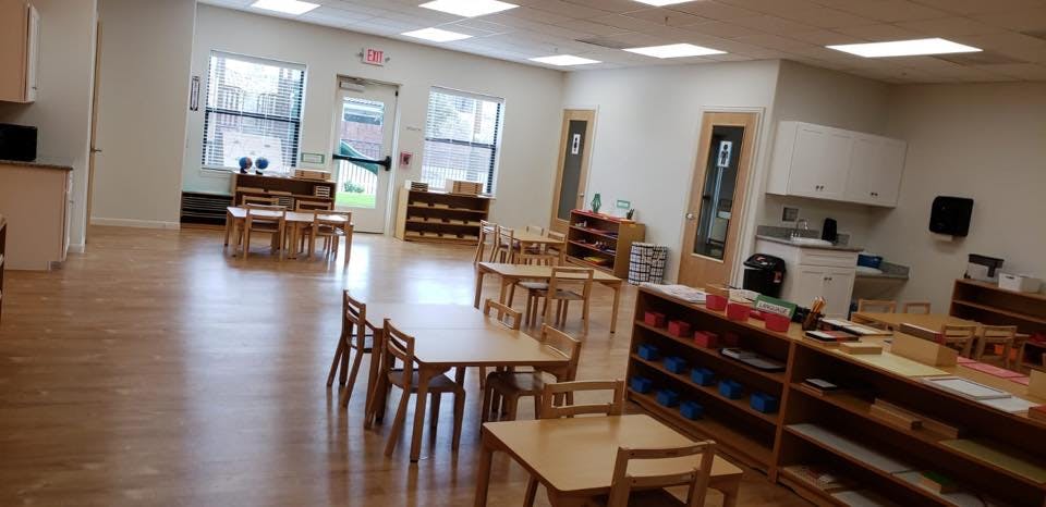 Empty classroom with small wooden tables and chairs