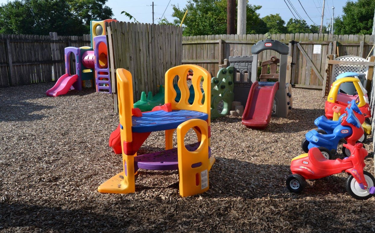 Outdoor playground with colorful plastic play structures and ride-on toys