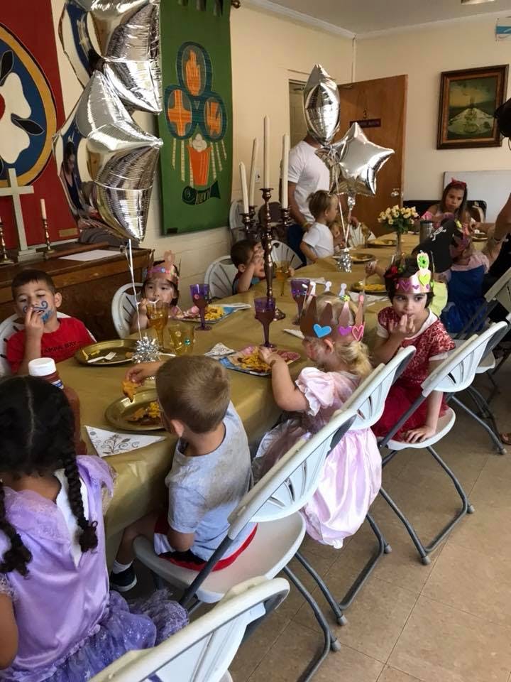 Children sitting at a long table eating