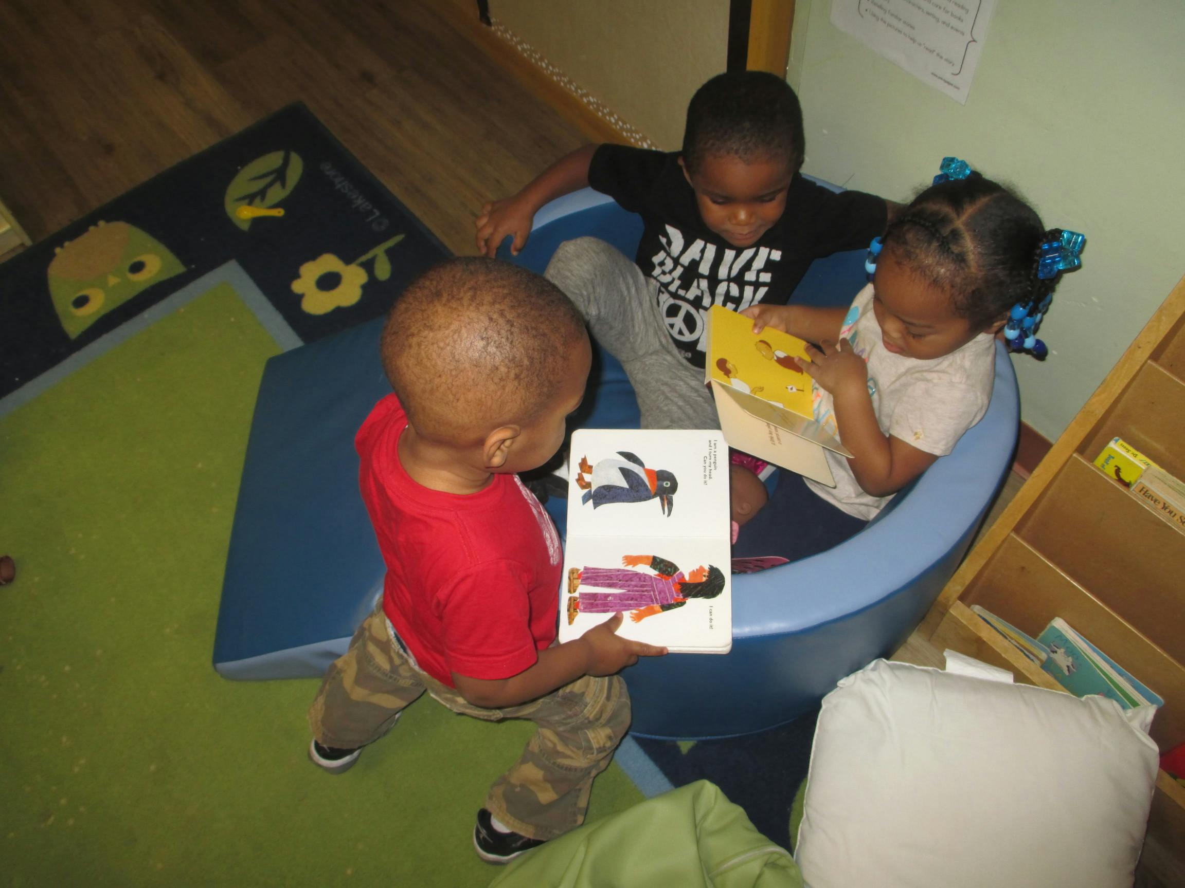 Three children looking at books in a classroom