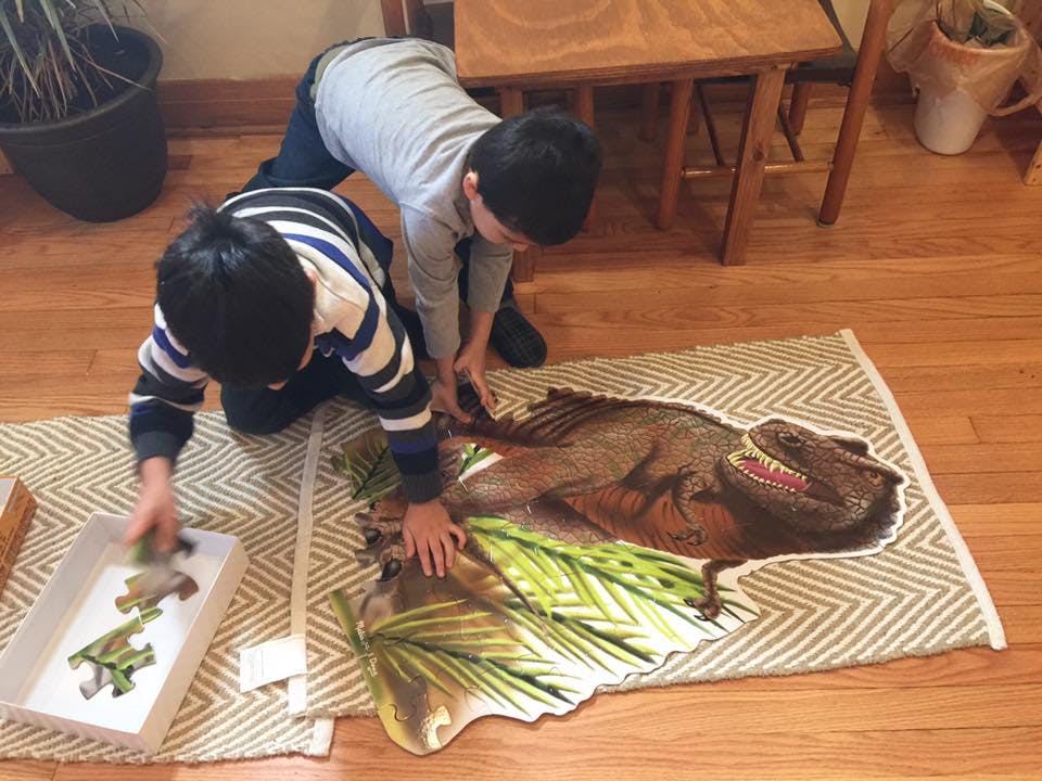 Two children assembling a dinosaur floor puzzle