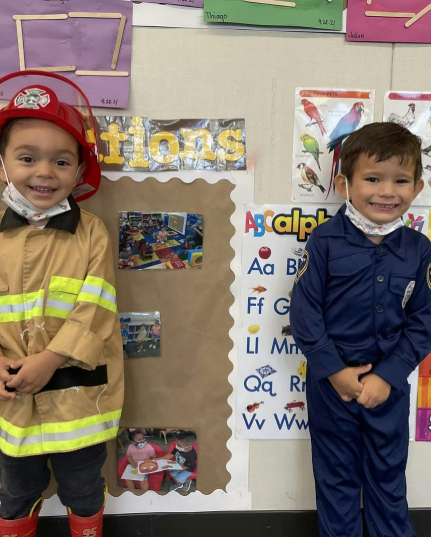 Two children in costumes, one in a firefighter costume and one in a police uniform