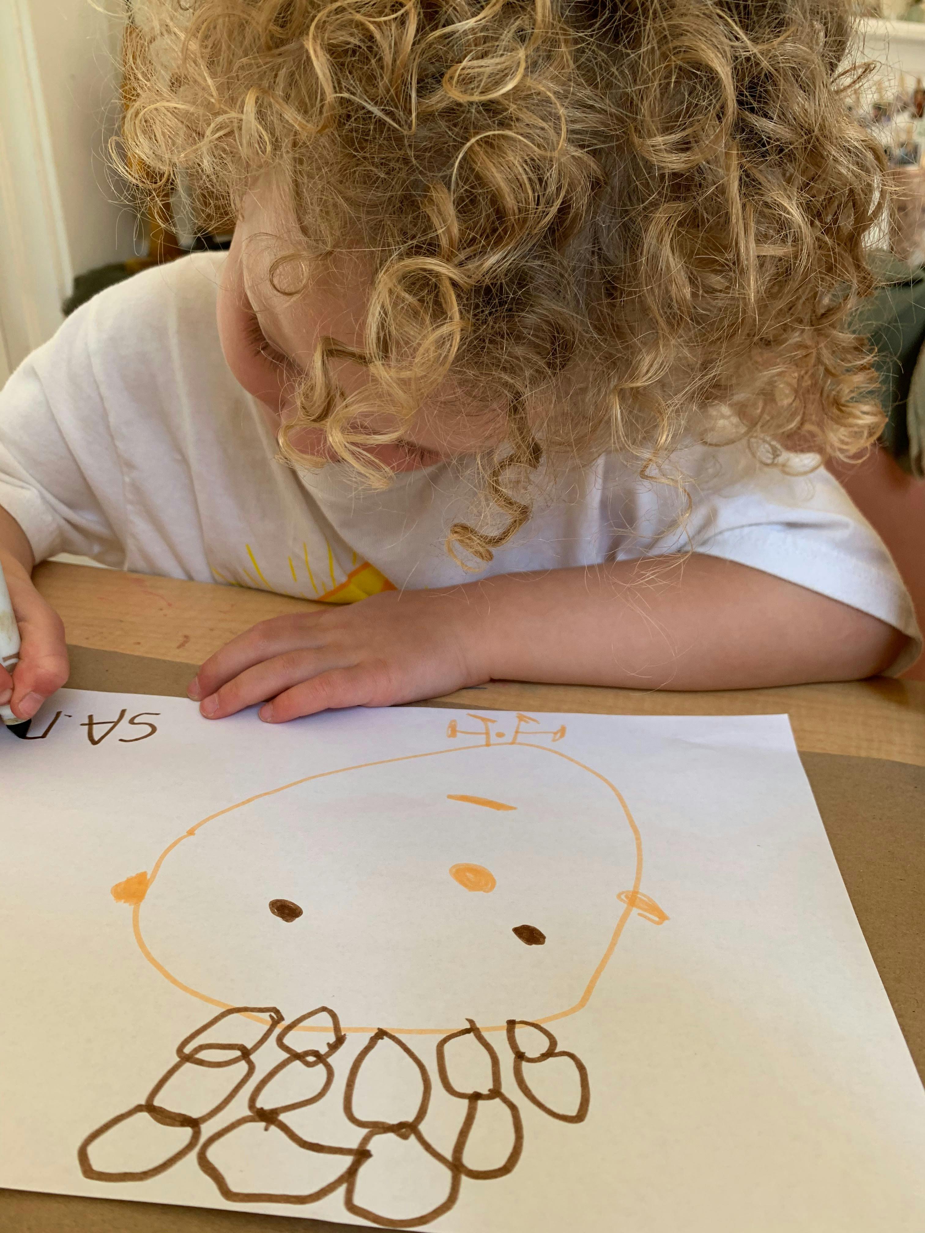 Child with curly hair drawing on paper