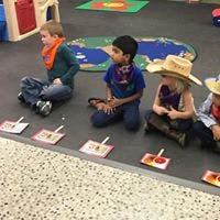 Four children sitting on the floor in a classroom