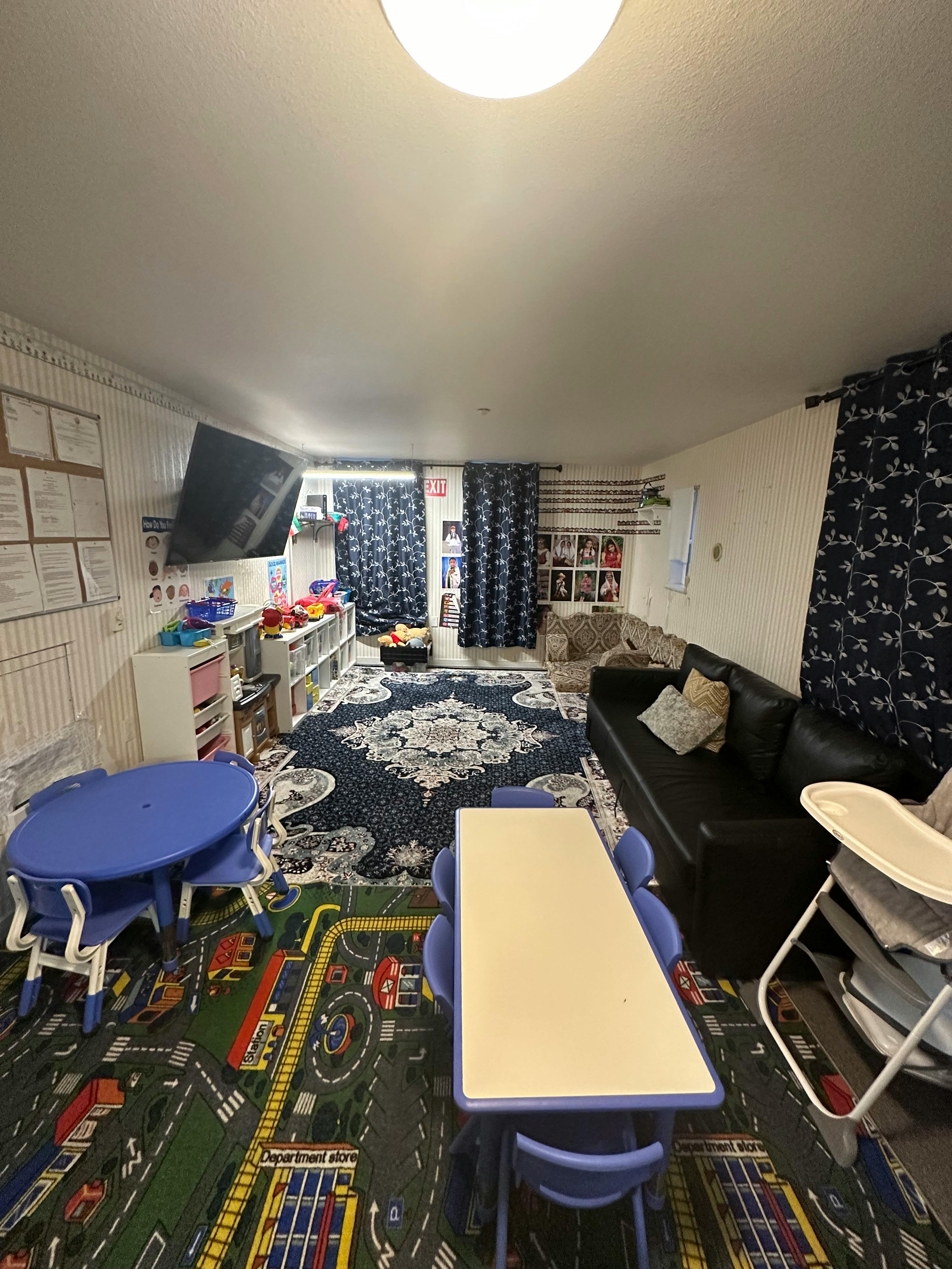 Playroom with small tables and chairs, a sofa, and a patterned rug