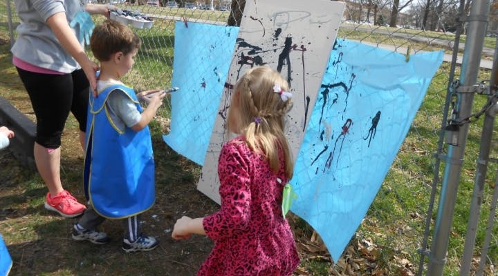 Child painting on blue paper outdoors