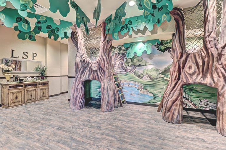 Indoor play area with tree-like structures and a painted mural