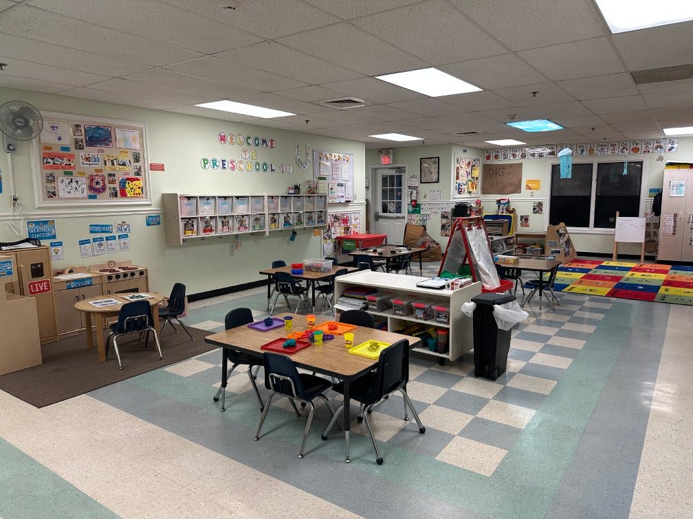 Empty preschool classroom with small tables and chairs