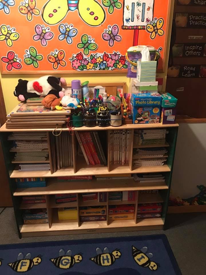 Bookshelf with books, art supplies, and stuffed animals in a classroom
