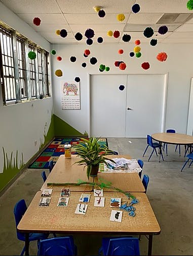 Classroom with tables, chairs, and colorful pom-poms hanging from the ceiling
