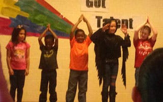 Five children performing on a stage