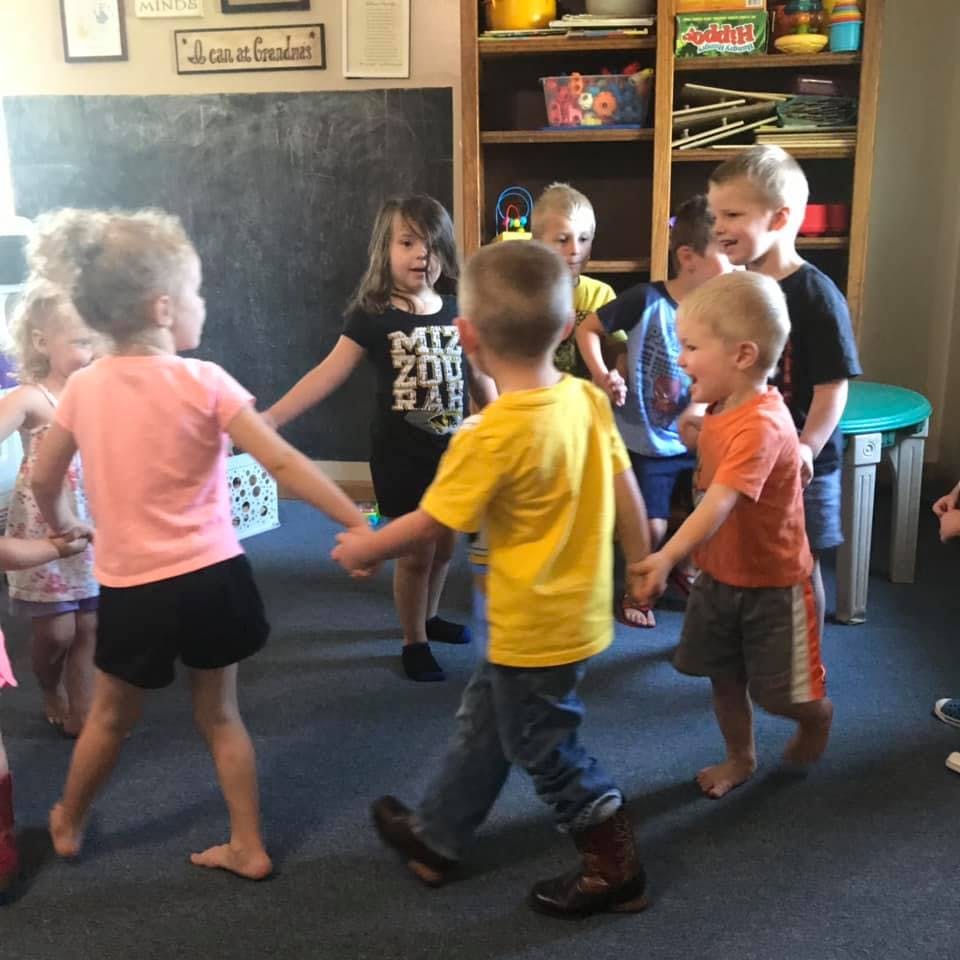 Children holding hands in a circle in a classroom