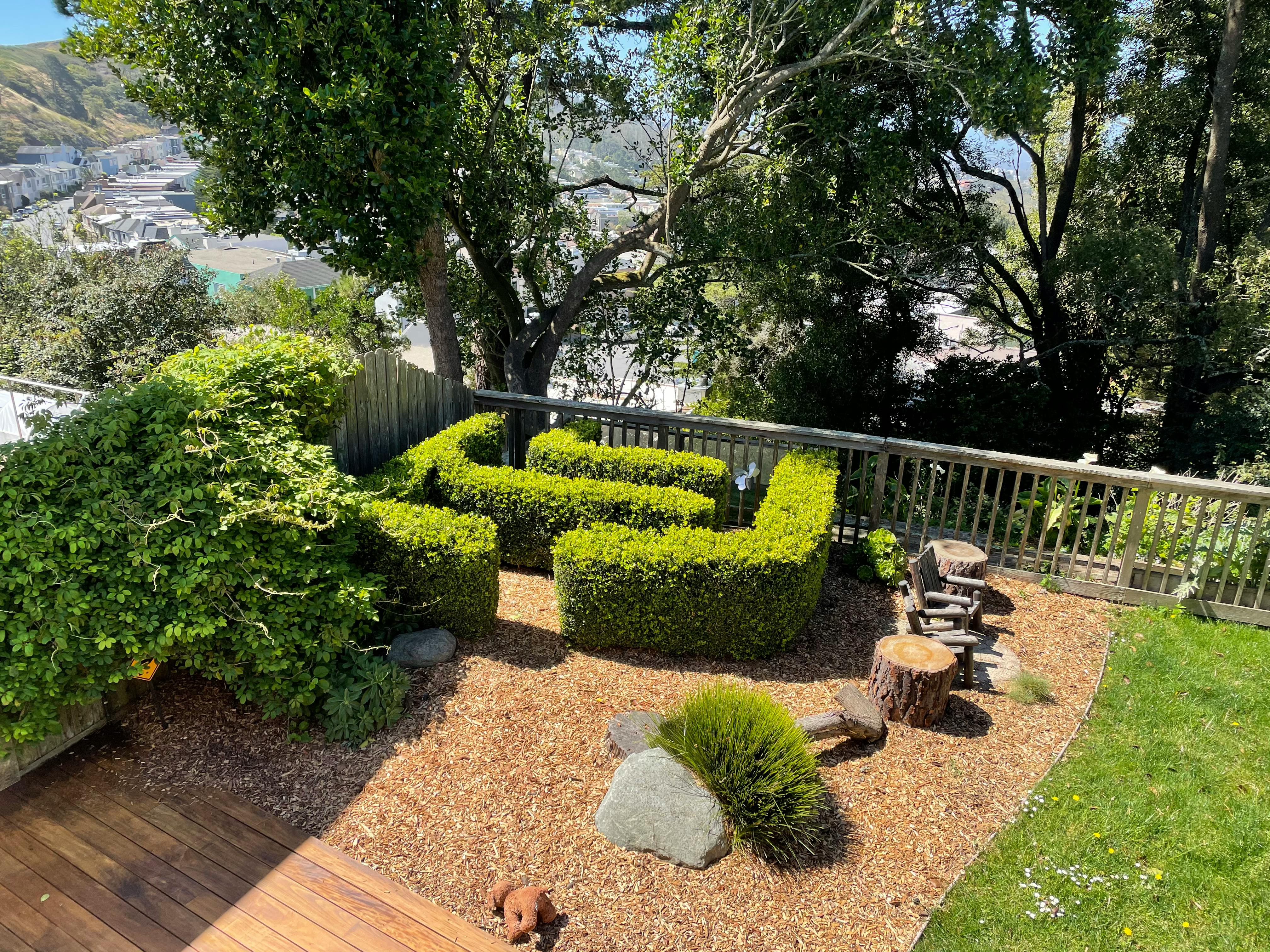 Garden with trimmed hedges and wooden fence overlooking a valley