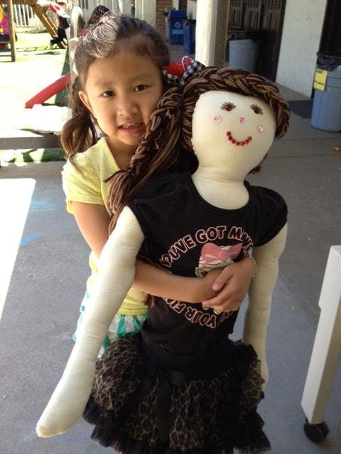 Child holding a large doll with braided hair