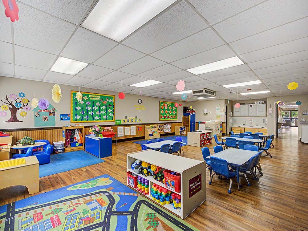 Empty classroom with small tables, chairs, and play areas