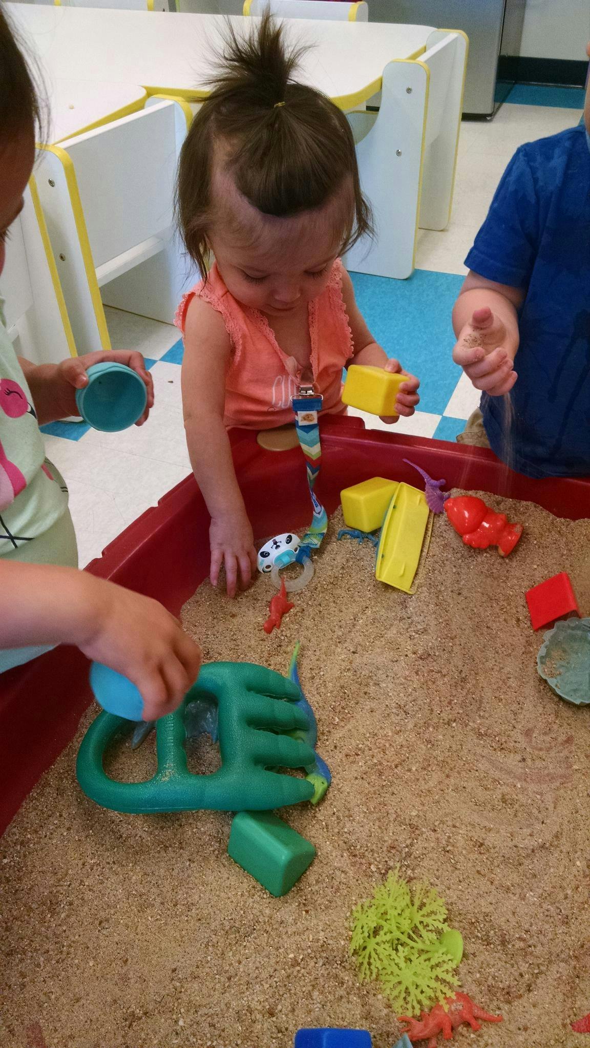 Children playing in a sand table with toys