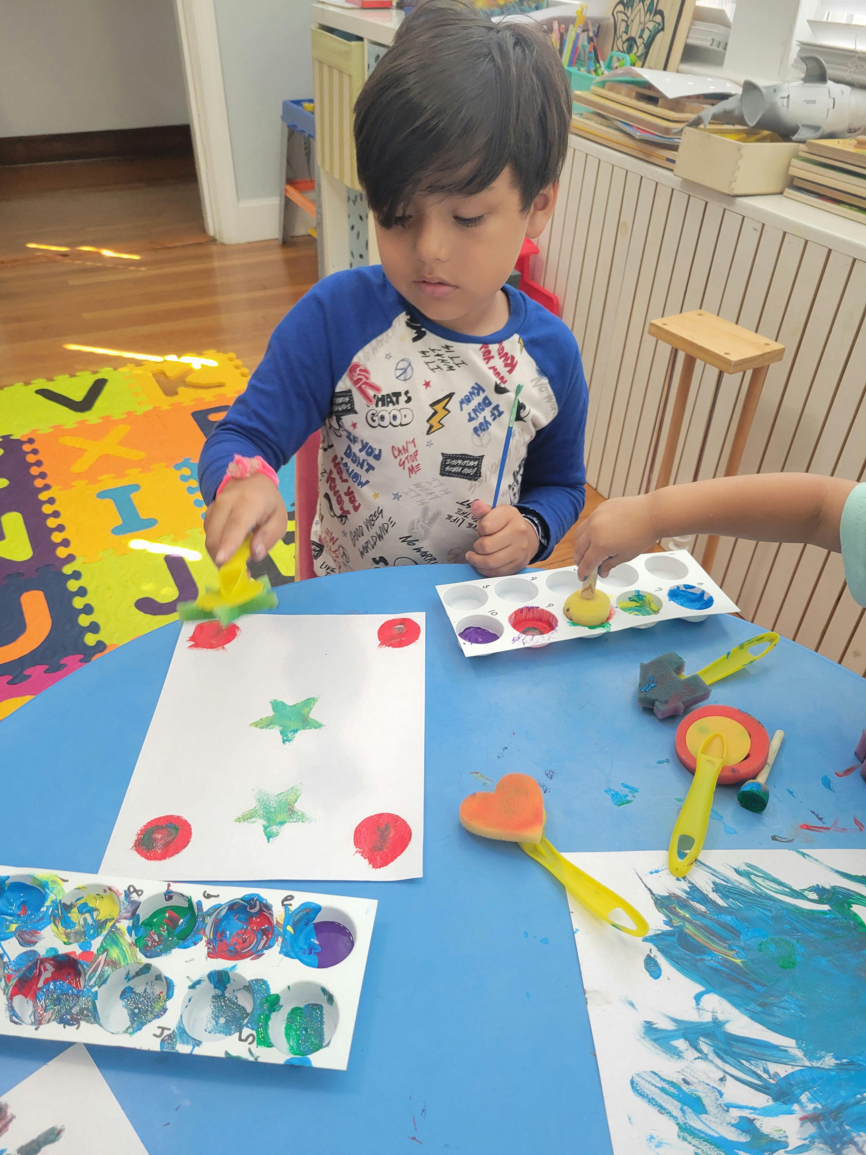 Child painting with sponges at a table