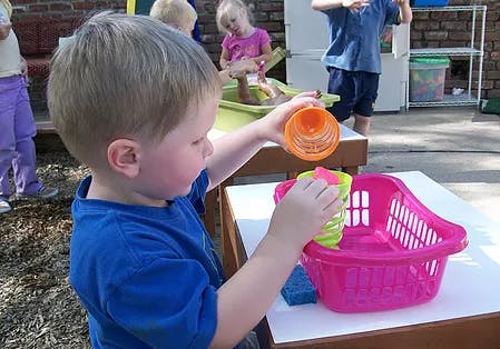 Child playing with plastic cups and a pink basket
