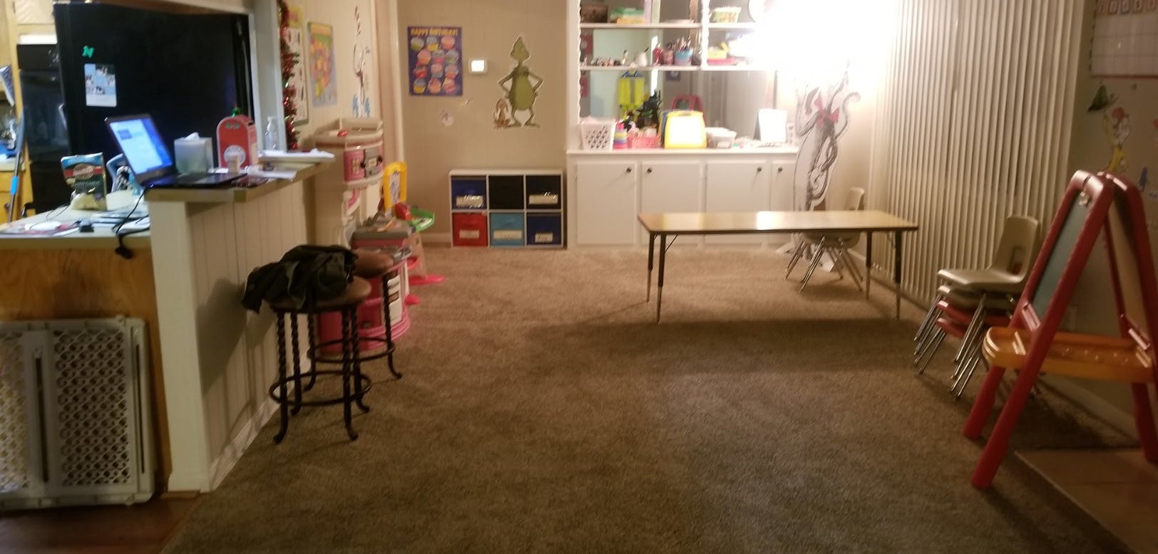 A room with a laptop on a counter, a table, and an easel