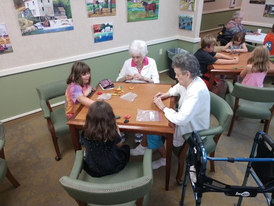 People and children sitting at tables doing activities