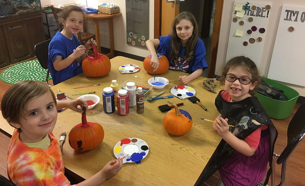Children painting pumpkins at a table