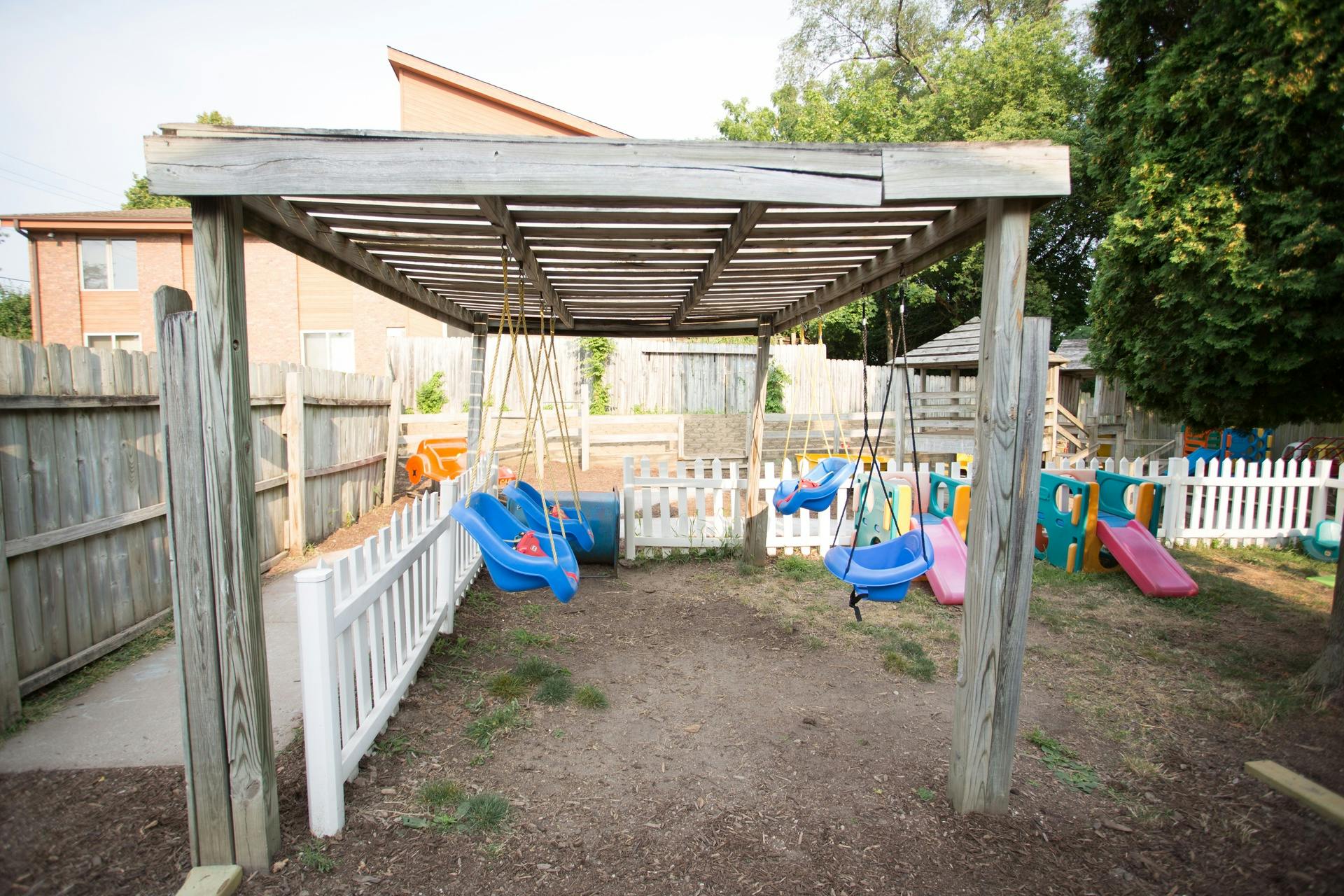 Playground with swings and slides under a wooden pergola