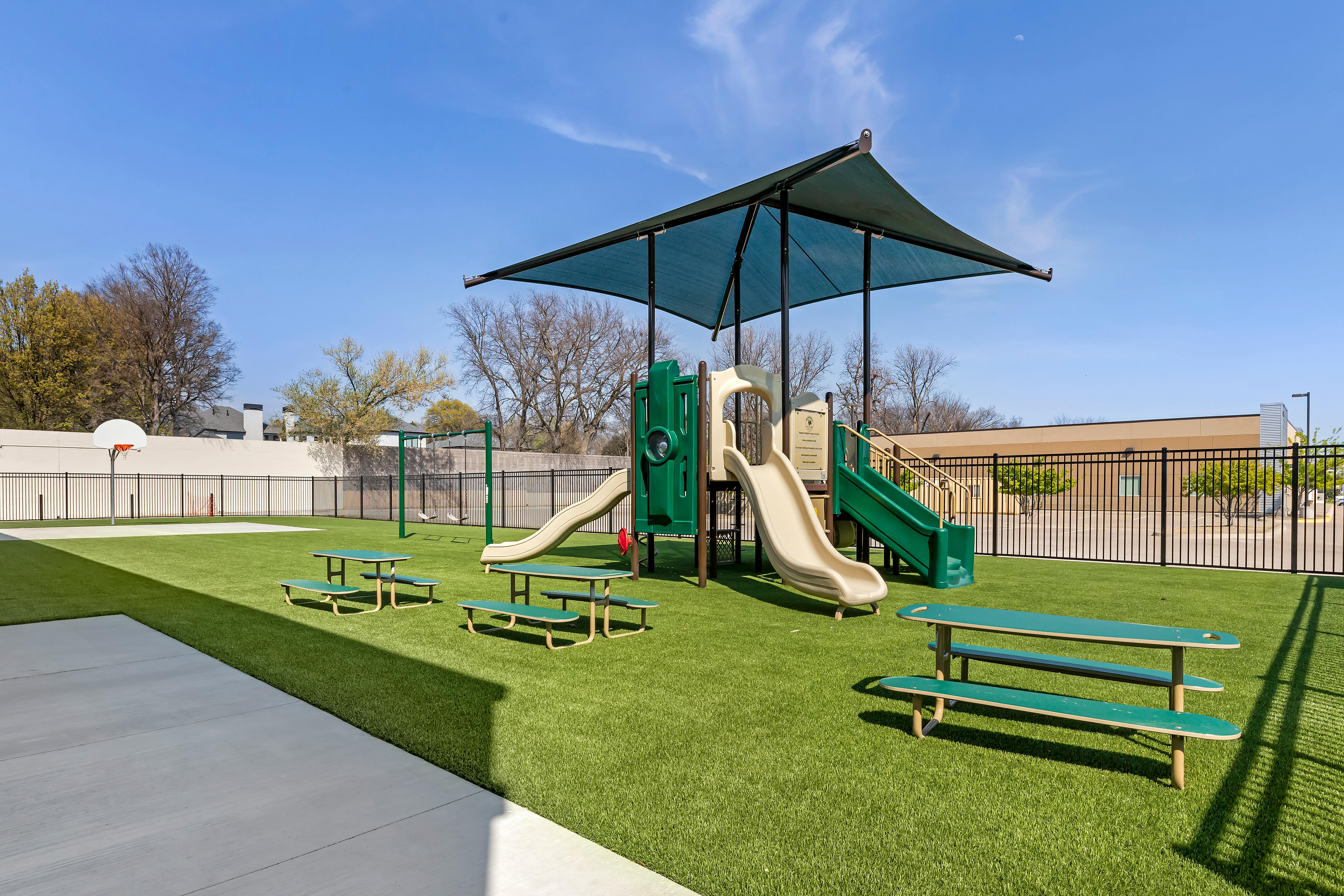 Outdoor playground with slides, picnic tables, and artificial turf