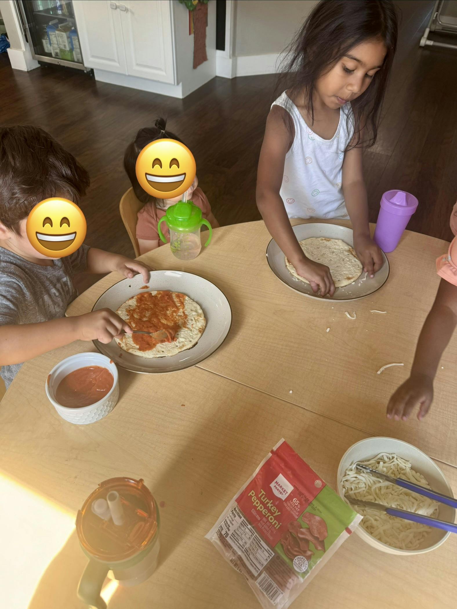 Children sitting at a table making personal pizzas