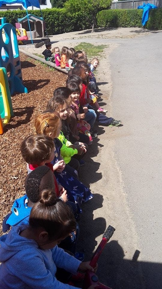 Children sitting in a line outdoors