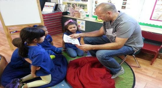 Adult showing paper to children in a classroom