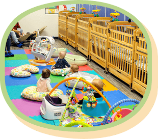 Babies playing on a colorful mat in a room with cribs