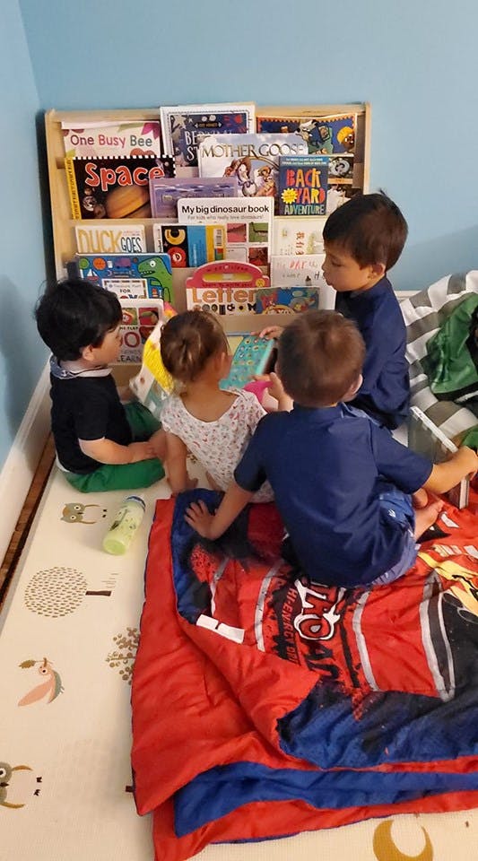 Four children sitting on the floor looking at books