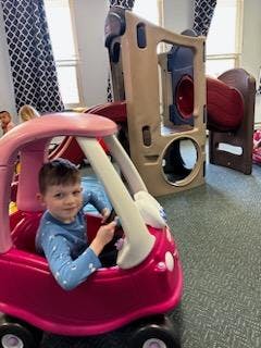 Child in a toy car indoors