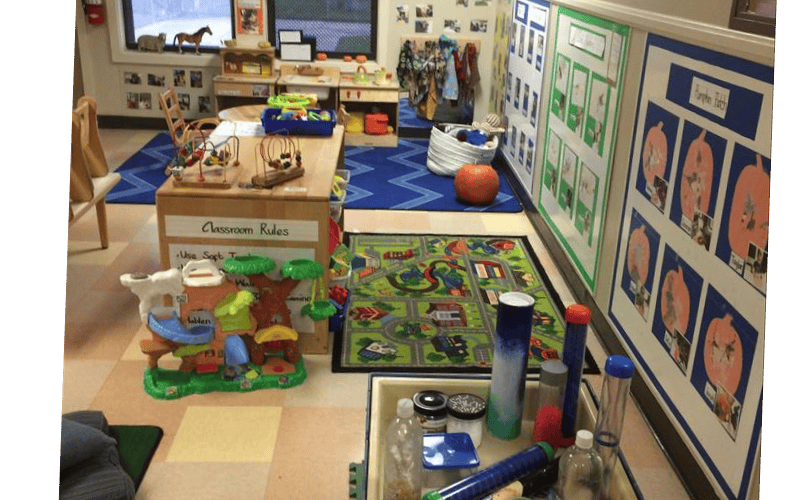 Classroom with children's toys, tables, and art displayed on the walls