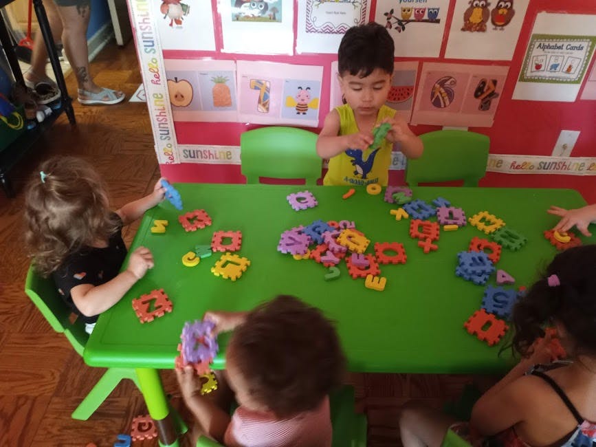 Children playing with colorful interlocking gears at a green table