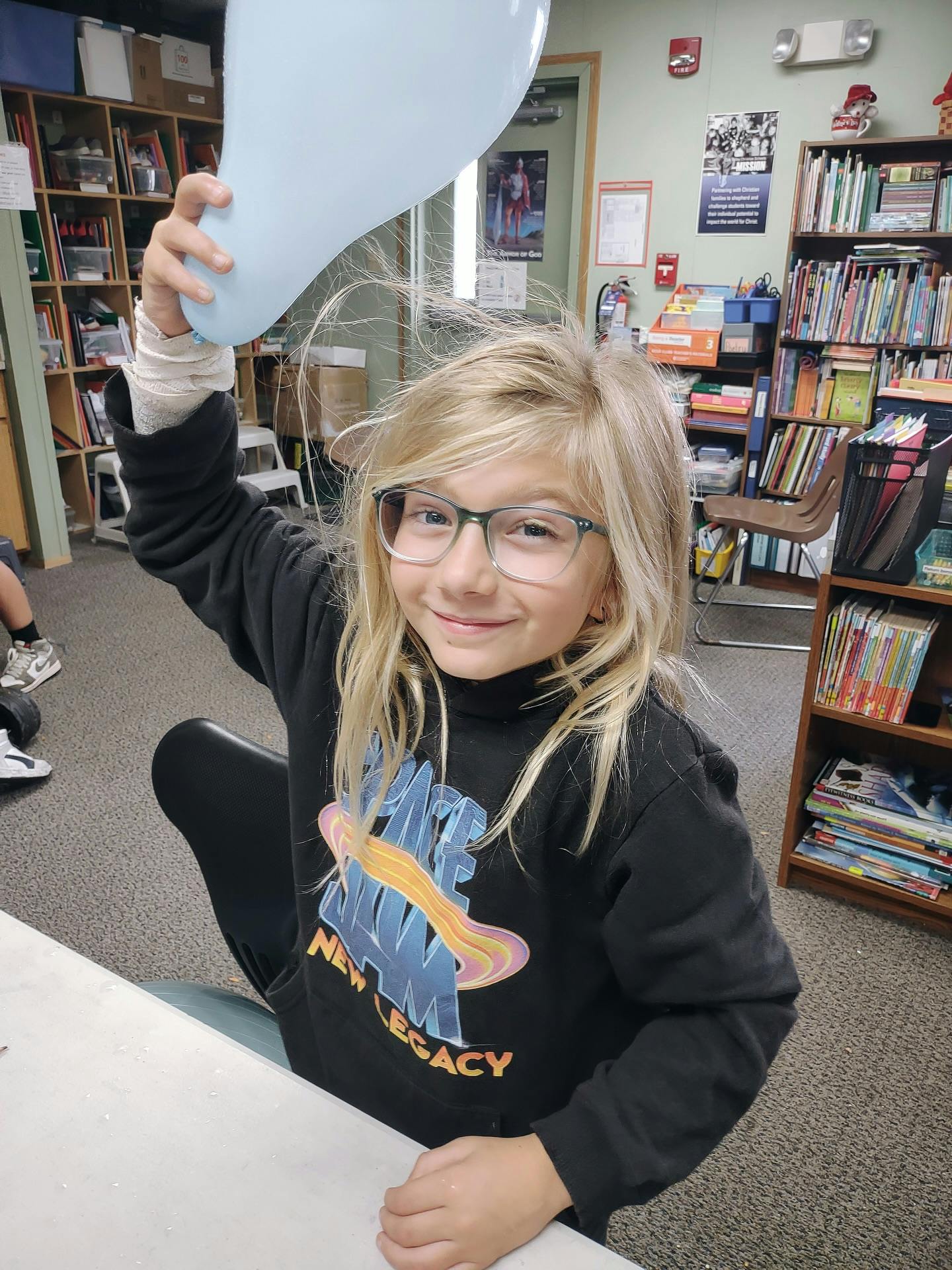 Child holding a balloon above their head, hair standing up from static electricity