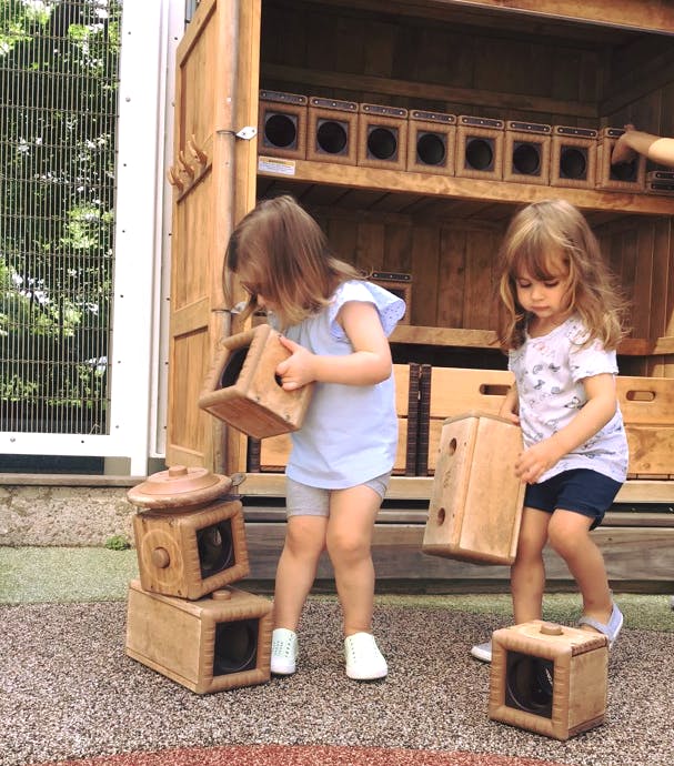 Two children playing with wooden boxes outdoors
