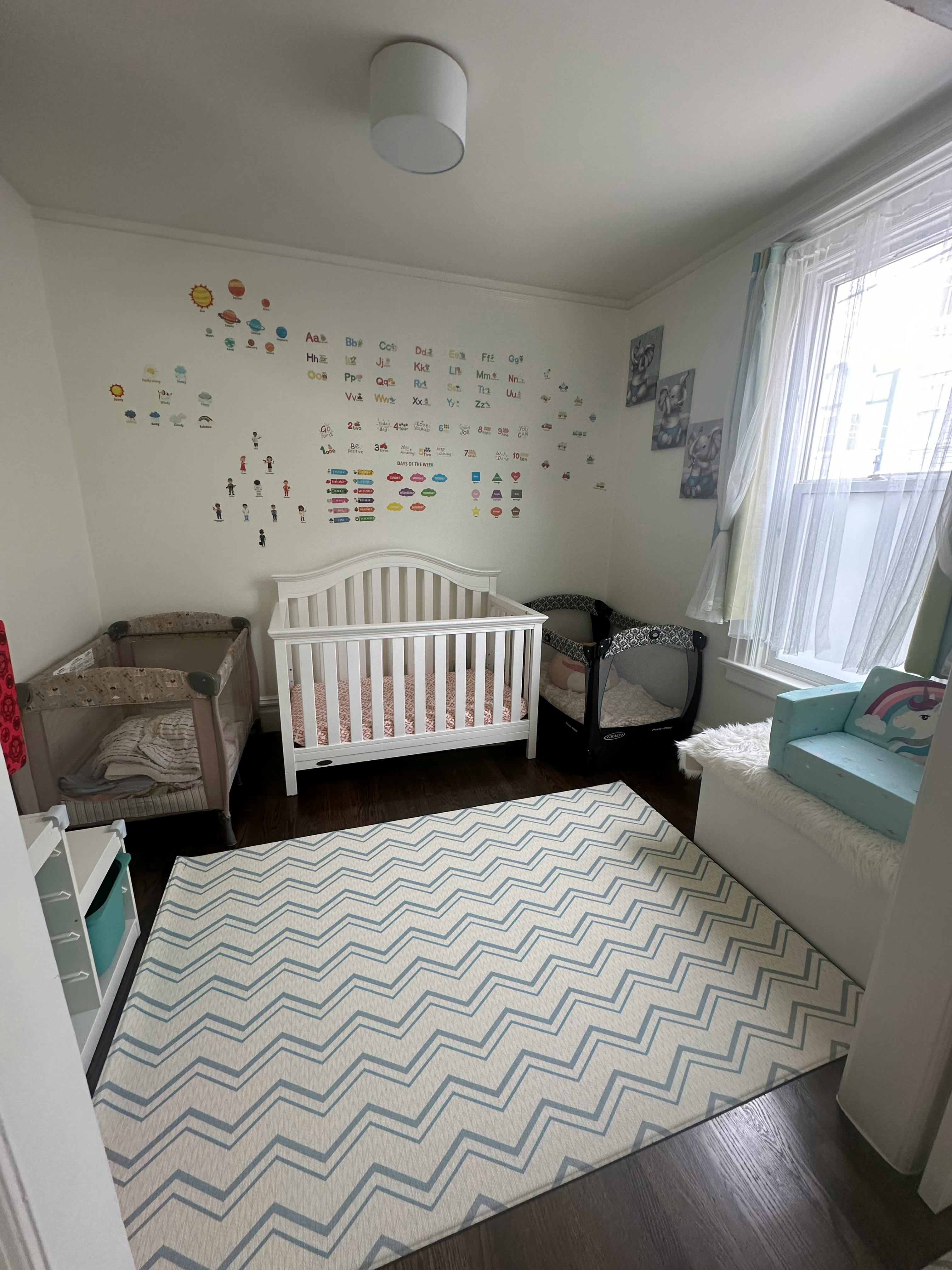 Nursery room with three cribs, a window, and a patterned rug