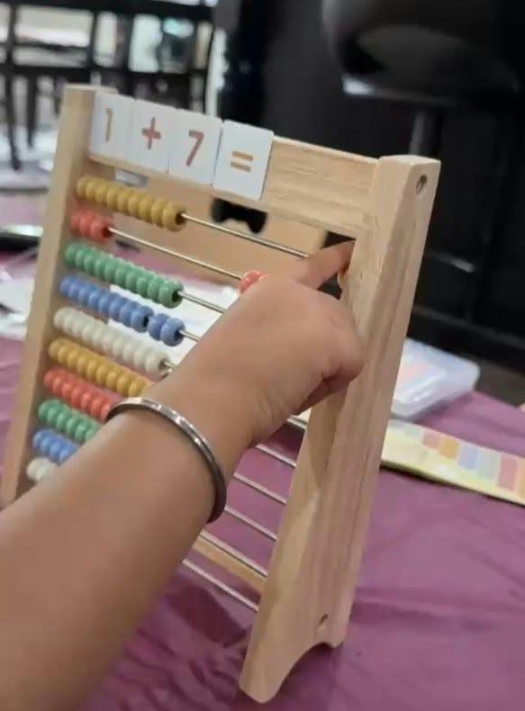 Person using an abacus to solve the math equation 1 plus 7