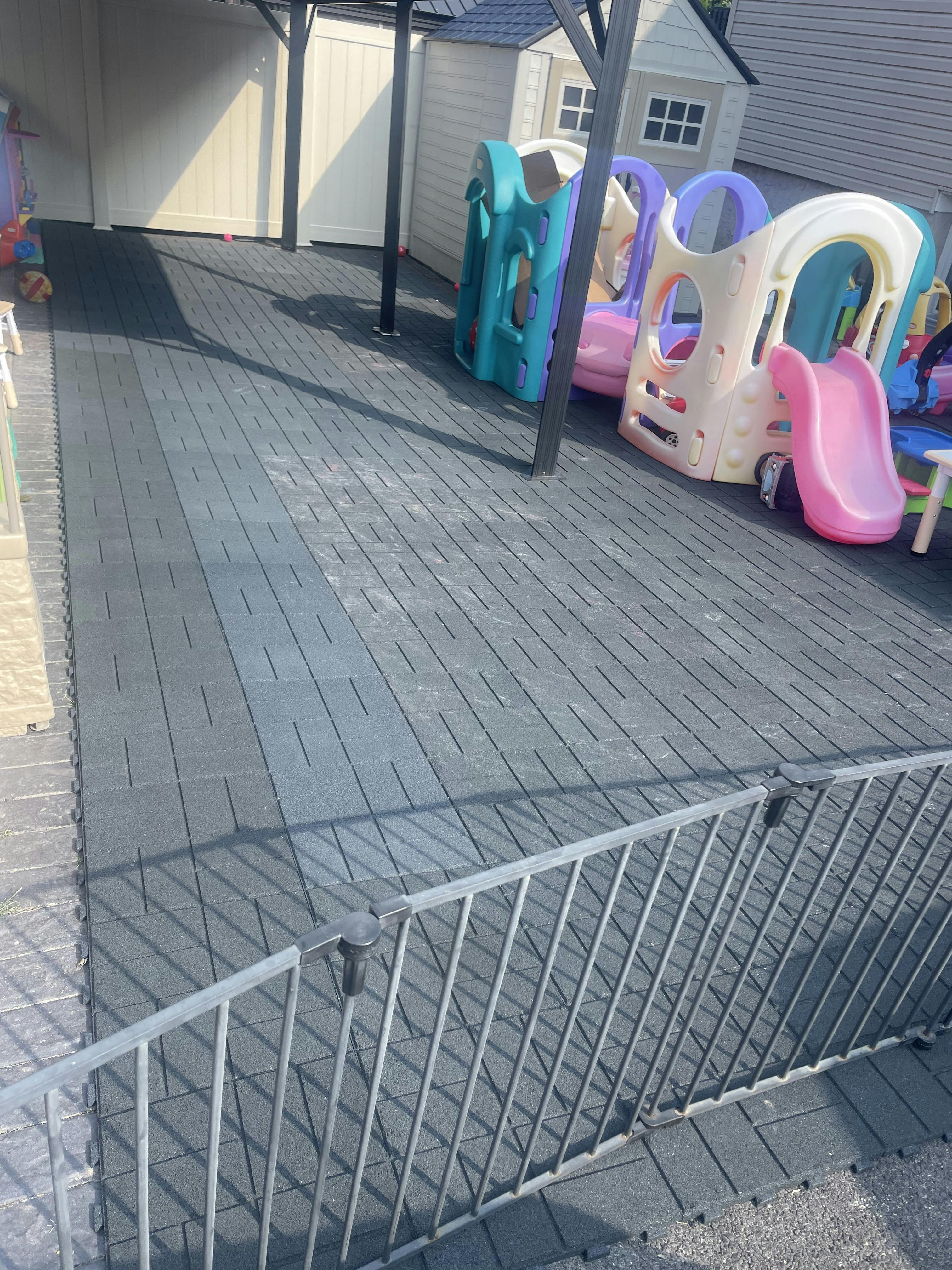 Outdoor play area with plastic slides and play structures on a dark tiled surface