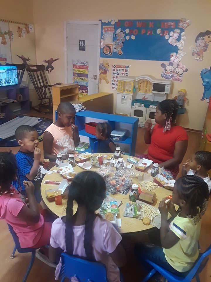 Adult and children sitting around a table eating in a classroom