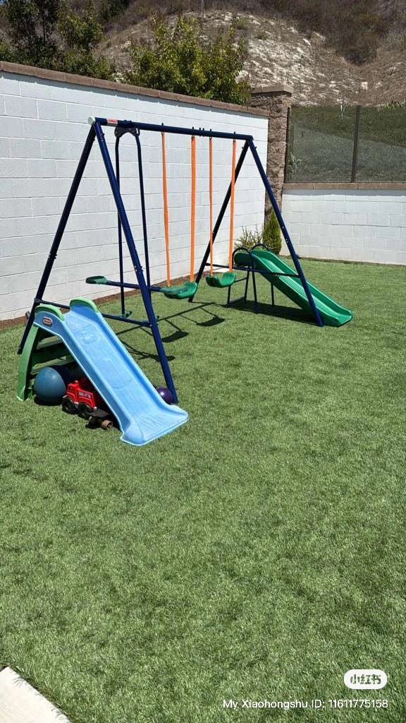 Swing set with two slides on green grass
