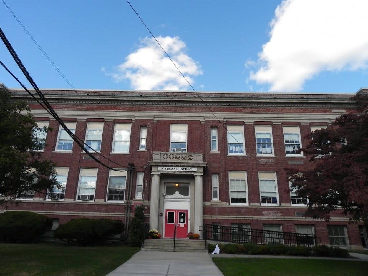 Brick building with red doors and a walkway leading to the entrance
