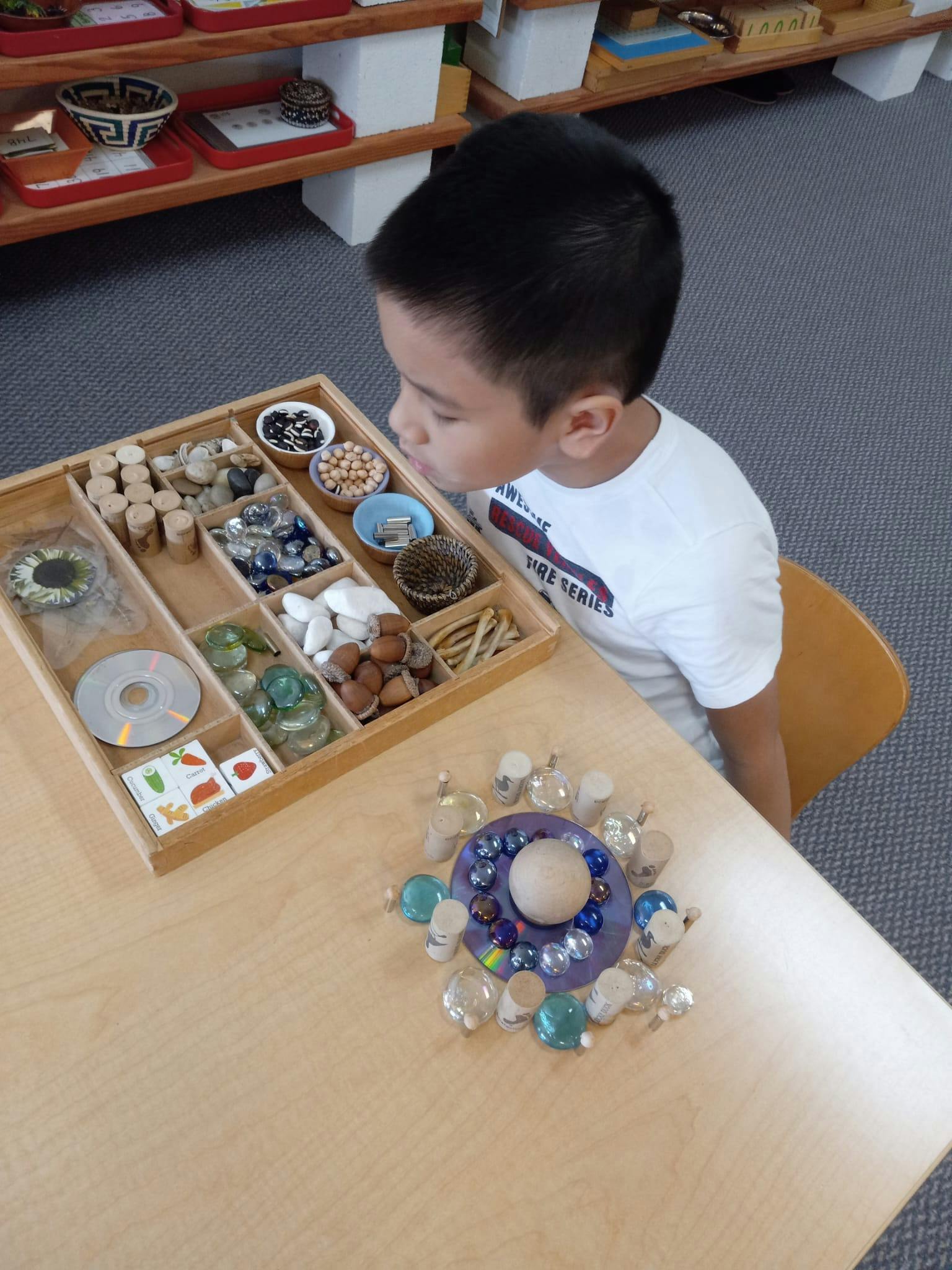 Child looking at a wooden tray with various small objects