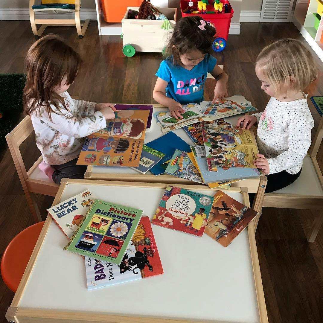 Three children sitting at a table looking at books