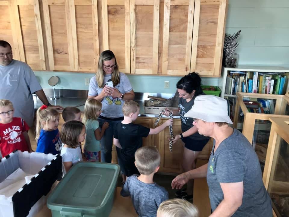 Adults and children gathered around a counter, one child holding a chain